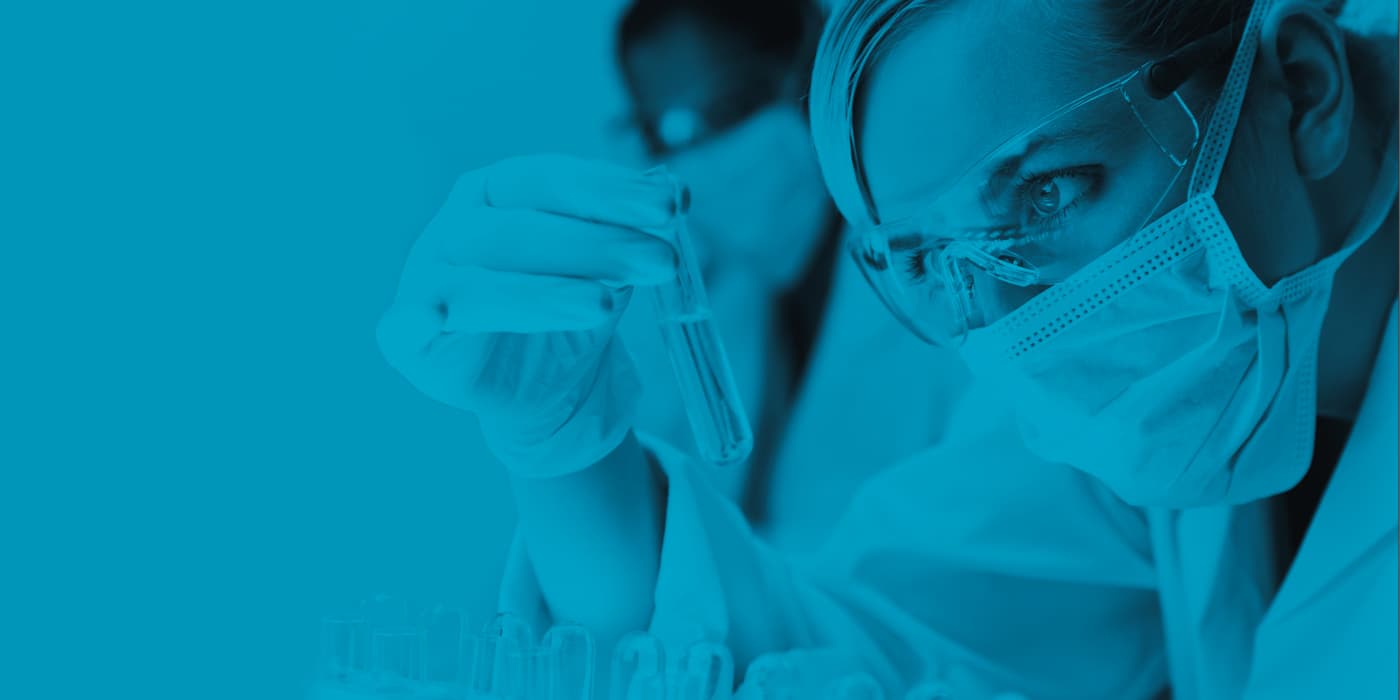 A scientist closely looking at a test tube.