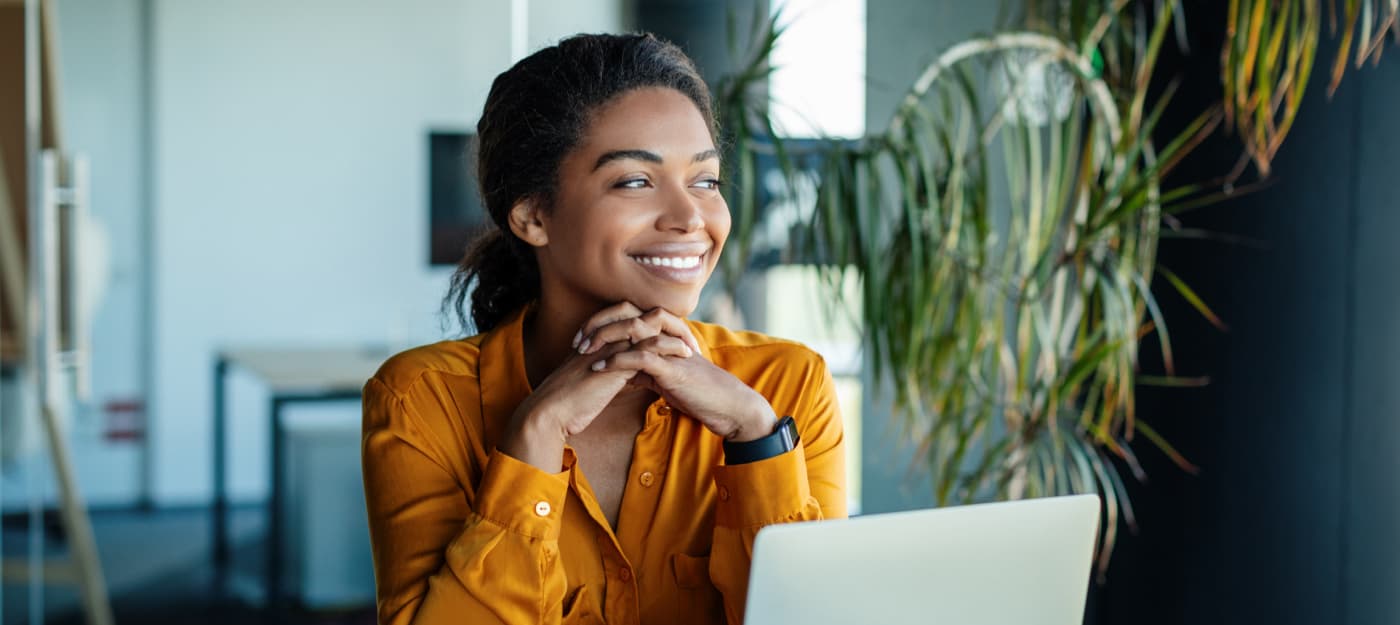 A smiling young woman sitting at a desk.